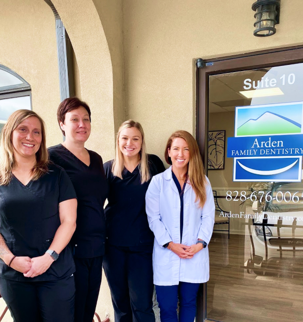 Four female dental staff members standing together in front of Arden Family Dentistry office entrance.