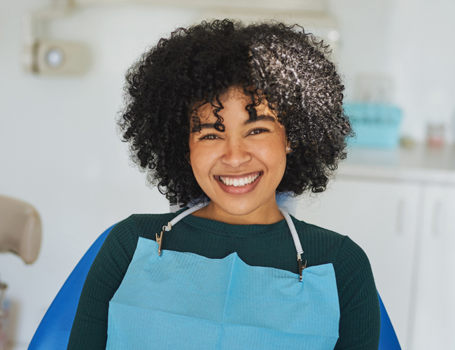 Smiling dental professional wearing blue apron in modern dental office setting.
