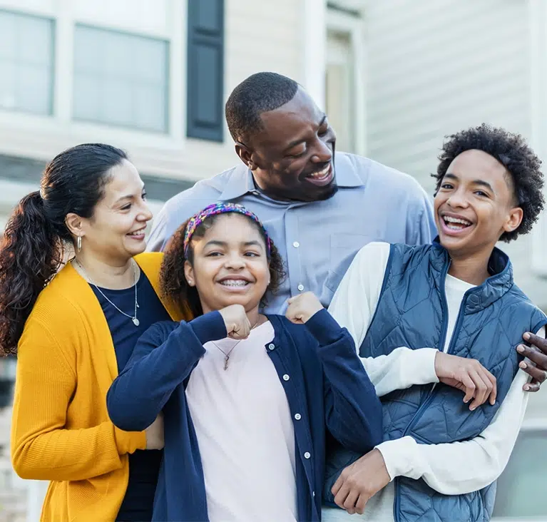 Happy family of four smiling together outdoors in casual clothing.
