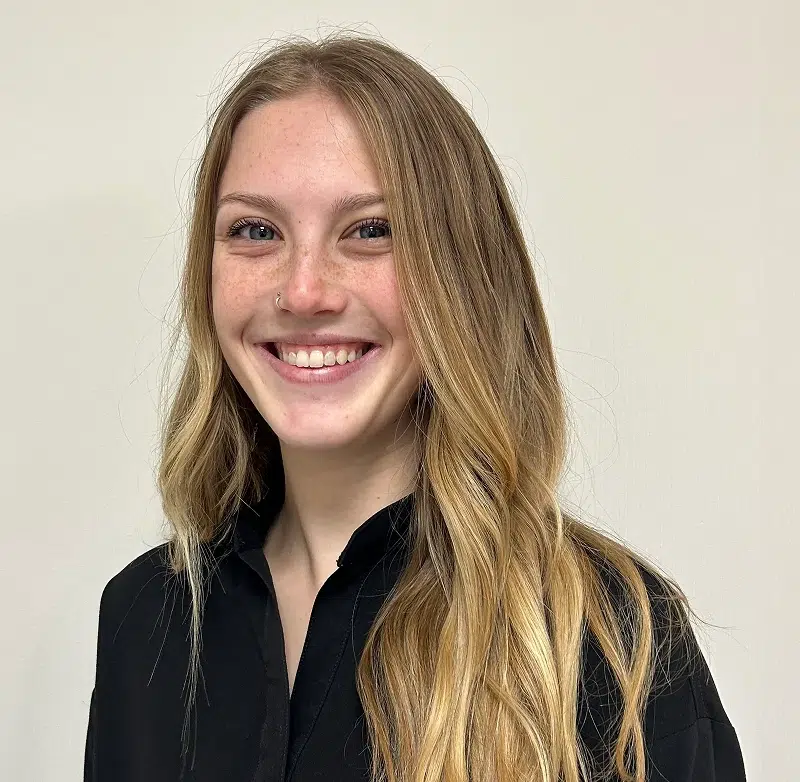 Young woman smiling at camera wearing black shirt against white background